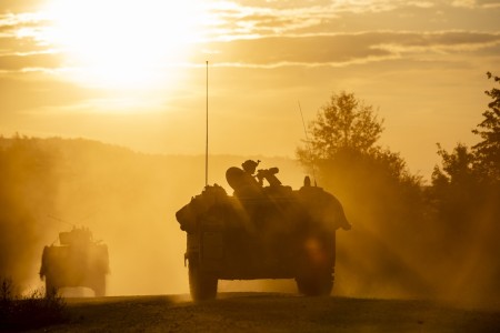A convoy of U.S. Army Soldiers and vehicles from 1st Battalion of the 4th Infantry Regiment, playing the role of opposition forces, rolls through a training village with various armored vehicles during Saber Junction 23 at the Joint Multinational...