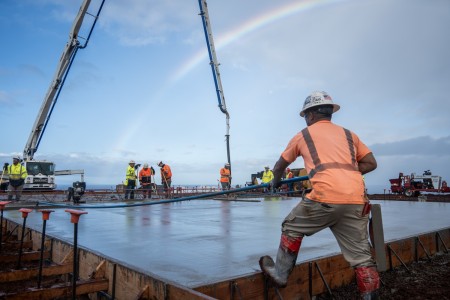 A contractor smooths concrete that is placed in the covered area at the temporary school, Dec. 29, 2023, in Lahaina, Hawaii....
